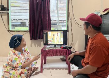 Ibu Mude (kiri), Masyarakat Desa Olu, kini dapat menikmati listrik dengan nyaman untuk aktivitas sehari-hari, termasuk menonton televisi tanpa lagi bergantung pada accu. Kehadiran listrik PLN membawa perubahan nyata bagi kualitas hidup masyarakat, membuka akses informasi melalui konektivitas digital saluran TV dan membuka peluang baru bagi peningkatan ekonomi masyarakat di wilayah terpencil. (Divkom PLN Pusat)