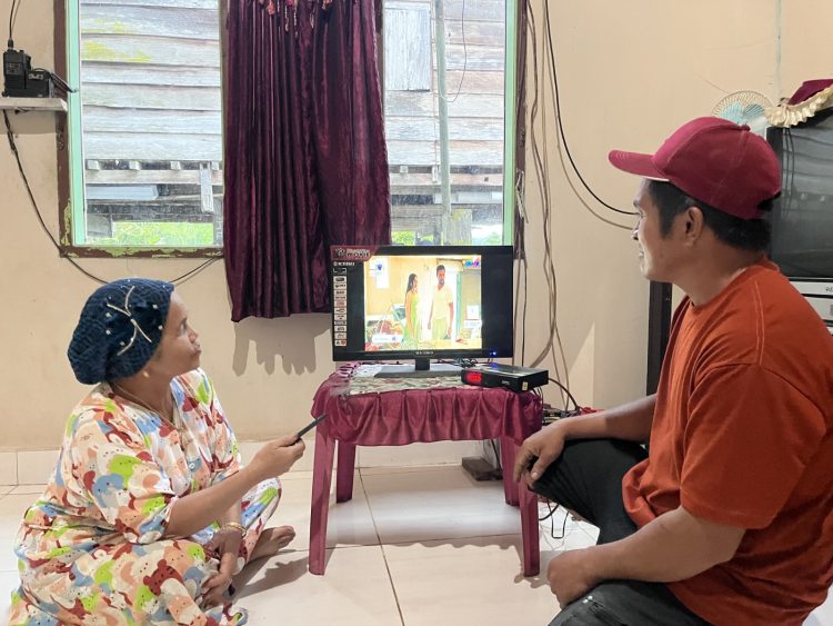 Ibu Mude (kiri), Masyarakat Desa Olu, kini dapat menikmati listrik dengan nyaman untuk aktivitas sehari-hari, termasuk menonton televisi tanpa lagi bergantung pada accu. Kehadiran listrik PLN membawa perubahan nyata bagi kualitas hidup masyarakat, membuka akses informasi melalui konektivitas digital saluran TV dan membuka peluang baru bagi peningkatan ekonomi masyarakat di wilayah terpencil. (Divkom PLN Pusat)