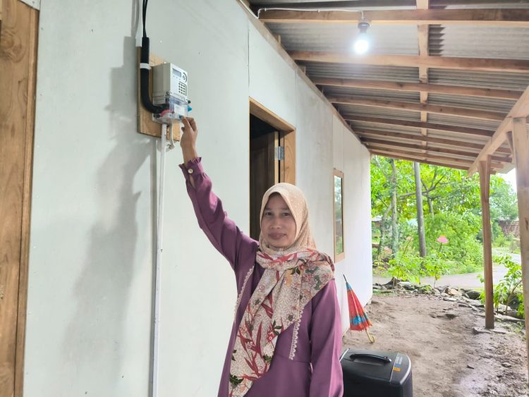 Karmini, warga Desa Ngandul, Kabupaten Sragen, Jawa Tengah di depan meter listrik miliknya sendiri, bantuan pemasangan listrik gratis dari PLN. Kini ia bisa menikmati listrik secara mandiri tanpa harus menumpang lagi. (Divkom PLN Pusat)