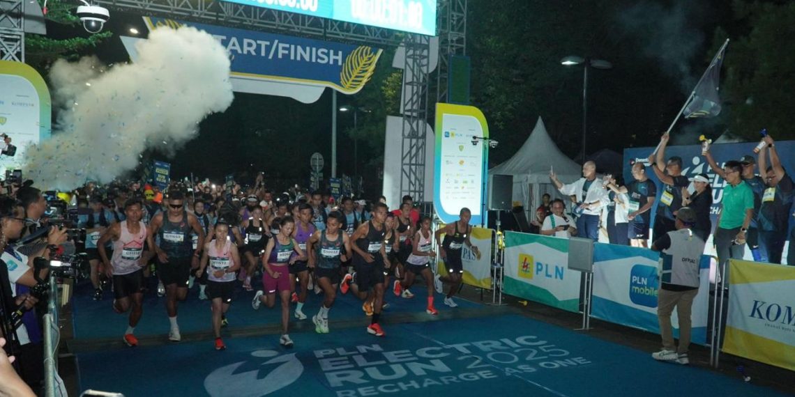 Direktur Utama PLN, Darmawan Prasodjo (belakang memegang bendera) bersama jajaran Direksi dan Komisaris PLN melepas para peserta Kategori Half Marathon PLN Electric Run 2025 di garis start. (Divkom PLN Pusat)