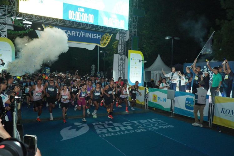 Direktur Utama PLN, Darmawan Prasodjo (belakang memegang bendera) bersama jajaran Direksi dan Komisaris PLN melepas para peserta Kategori Half Marathon PLN Electric Run 2025 di garis start. (Divkom PLN Pusat)