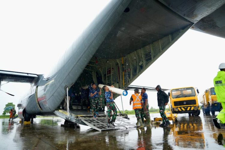 Personel TNI AU menurunkan material tower emergency dari ruang kargo pesawat Hercules di tengah kondisi hujan. Proses bongkar muat dilakukan secara cepat untuk mempercepat tahapan penyaluran ke area pemulihan kelistrikan. (Divkom PLN Pusat/ PLN UID Aceh)