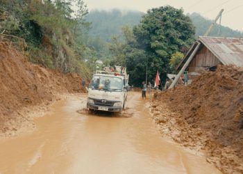 Armada pengangkut material PLN berupaya melewati jalur penuh lumpur pascabencana banjir dan tanah longsor di Aceh. Kerusakan masif pada jembatan penghubung dan akses jalan nasional maupun provinsi menjadi tantangan utama dalam mobilisasi material kelistrikan menuju lokasi-lokasi terdampak. (Divkom PLN Pusat)