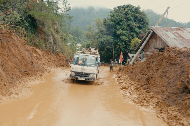 Armada pengangkut material PLN berupaya melewati jalur penuh lumpur pascabencana banjir dan tanah longsor di Aceh. Kerusakan masif pada jembatan penghubung dan akses jalan nasional maupun provinsi menjadi tantangan utama dalam mobilisasi material kelistrikan menuju lokasi-lokasi terdampak. (Divkom PLN Pusat)
